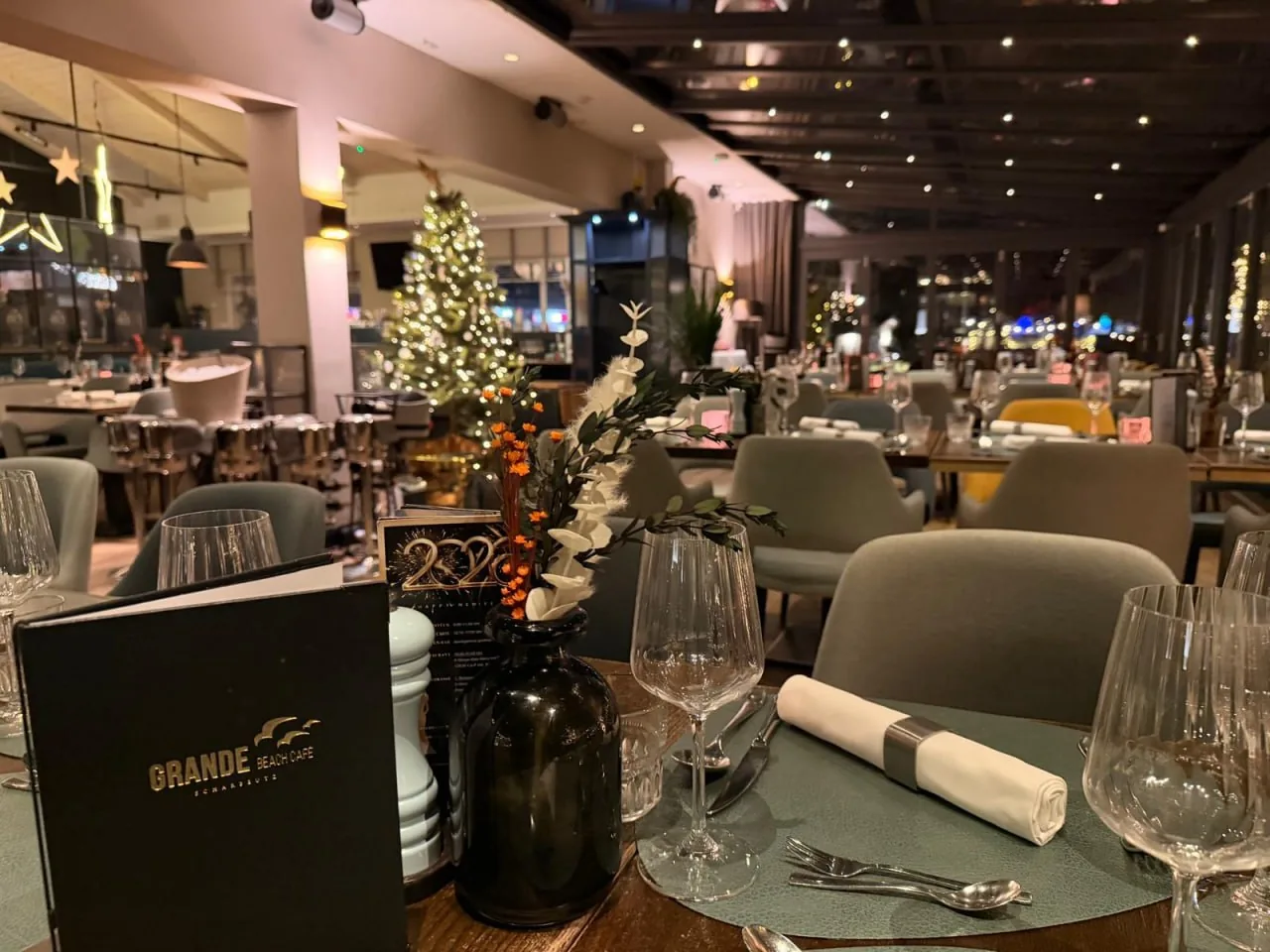 Gedeckter Tisch mit Weihnachtsbaum und Lichtern im Grande Beach Café